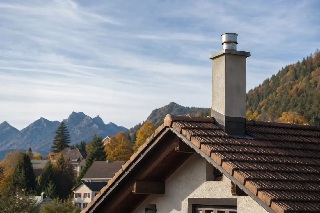 Conduit de cheminée et souche en toiture d'une maison de Suisse romande